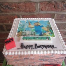 A personalised photo cake with a Minecraft photo on the front. The cake is square in shape and white in colour.