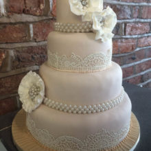 A wedding cake decorated with icing lace and flowers.