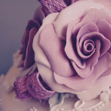 Purple icing rose placed on top of a wedding cake.