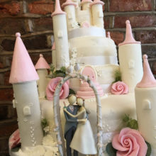 A wedding cake shaped like a castle with two icing figures in front. The cake is on display in a cake shop in Wolverhampton.