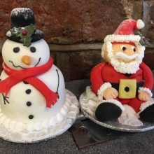 Two bespoke cakes. One looks like a Santa and the other like a snowman.